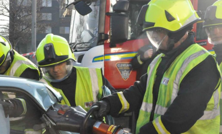 A group of firefighters using a heavy grinder to access a crashed car A group of firefighters using a heavy grinder to access a crashed car